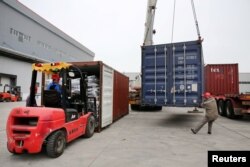 FILE - Men work on unloading the rubber imported from Belt and Road Initiative (BRI) countries at a bonded logistics center in Nantong, Jiangsu province, China, May 17, 2019.