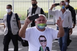 A supporter of Brazilian President Jair Bolsonaro, wearing a face mask amid the new coronavirus pandemic and a T-shirt covered in pro-Bolsonaro messages, yells at journalists in Brasilia, Brazil, May 25, 2020.