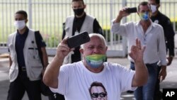 A supporter of Brazil's President Jair Bolsonaro, wearing a T-shirt covered in pro-Bolsonaro messages, yells at journalists after the president's departure from his official residence of Alvorada palace in Brasilia, May 25, 2020. 