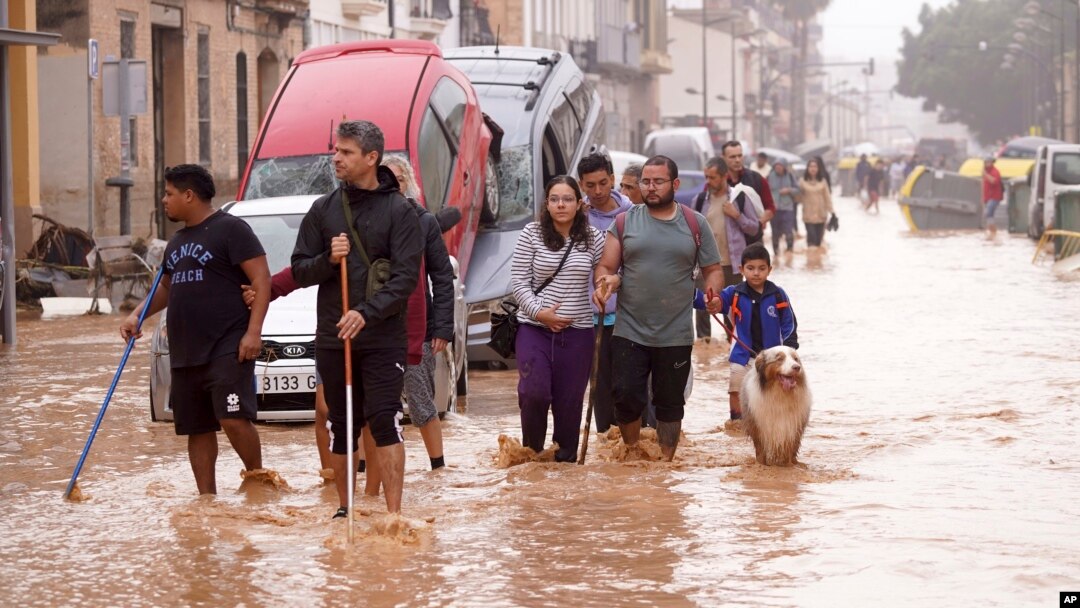 Warga berjalan melewati jalanan yang tergenang banjir di Valencia, Spanyol, pada 30 Oktober 2024. (Foto: AP/Alberto Saiz)