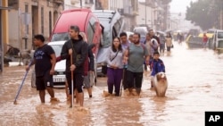 Warga berjalan melewati jalanan yang tergenang banjir di Valencia, Spanyol, pada 30 Oktober 2024. (Foto: AP/Alberto Saiz)