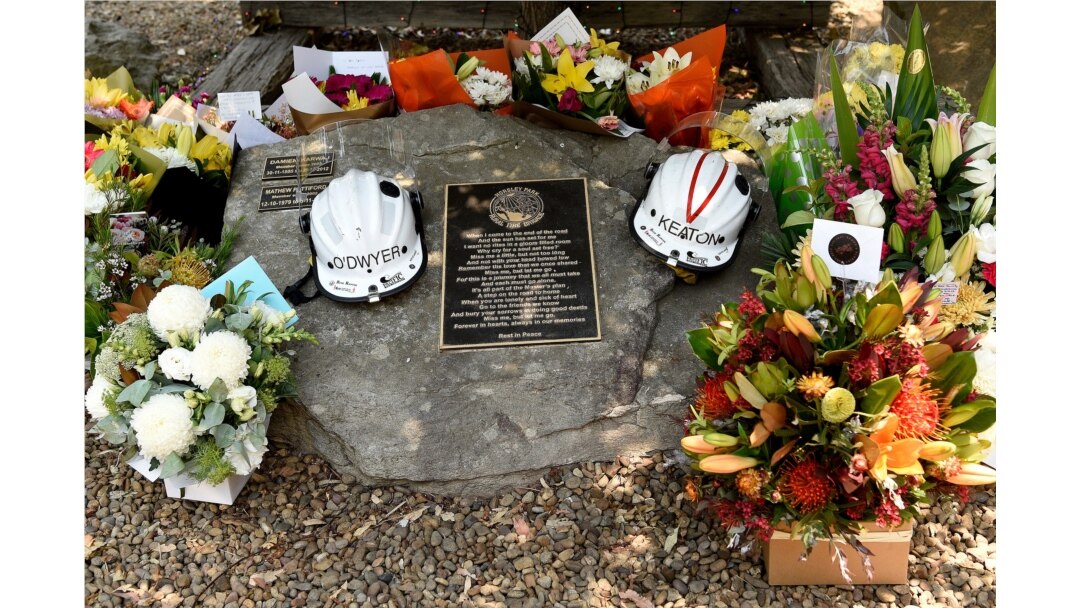 Flowers and the helmets of volunteer firefighters Andrew O'Dwyer and Geoffrey Keaton, who died when their firetruck was struck by a falling tree as it traveled through a fire, are seen at a memorial n Horsley Park, Australia, Dec. 20, 2019.