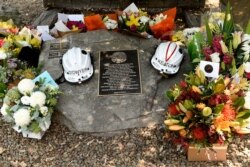 Flowers and the helmets of volunteer firefighters Andrew O'Dwyer and Geoffrey Keaton, who died when their firetruck was struck by a falling tree as it traveled through a fire, are seen at a memorial n Horsley Park, Australia, Dec. 20, 2019.