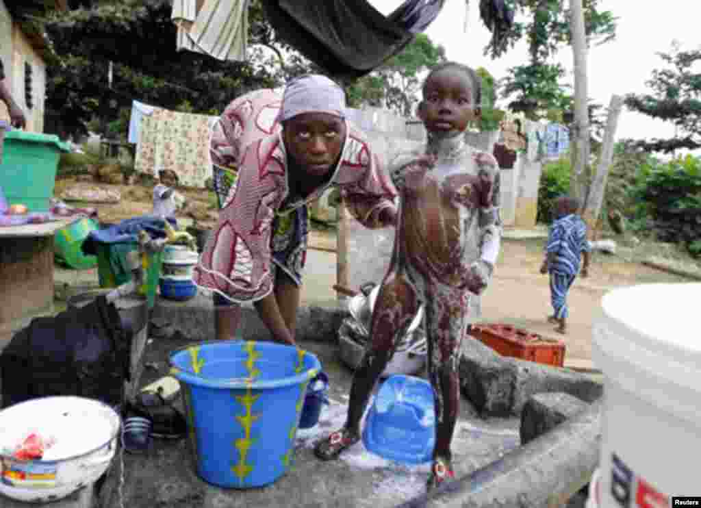 A Gabonese woman showers her daughter at the door of her house in Franceville, south of Libreville January 21, 2012.