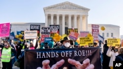 FILE-Stephen Parlato of Boulder, Colo., holds a sign that reads 'Hands Off Roe!!!' as abortion rights advocates and anti-abortion protesters demonstrate in front of the U.S. Supreme Court, Dec. 1, 2021, in Washington. 