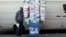A man talks from a public phone booth covered with various personal ads including job offers, jobs wanted and rooms for rent, in Madrid, Spain, Nov. 6, 2013. 