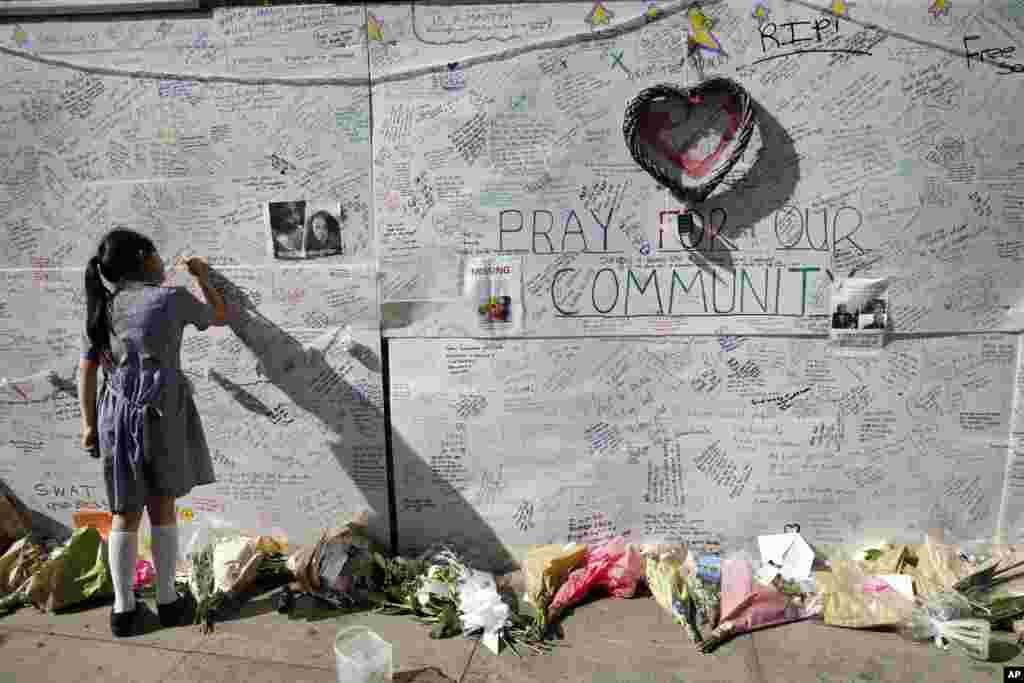 A school girl writes a message of support on a wall for the victims and those affected by the massive fire at Grenfell Tower in London.