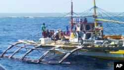 FILE - In this photo provided by Renato Etac, Chinese Coast Guard members, wearing black caps and orange life vests, approach Filipino fishermen as they confront them off Scarborough Shoal at South China Sea in northwestern Philippines, Sept. 23, 2015.