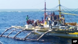 FILE - In this photo provided by Renato Etac, Chinese Coast Guard members, wearing black caps and orange life vests, approach Filipino fishermen as they confront them off Scarborough Shoal at South China Sea in northwestern Philippines, Sept. 23, 2015.