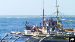 Foto dari Renato Etac, anggota penjaga pantai China, yang mengenakan topi hitam dan jaket orange, mendekati nelayan Filipina di Scarborough Shoal, Laut China Selatan di barat laut Filipina, 23 September 2015.