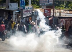 FILE - A man throws a tear gas canister back at the police during a protest against Haiti's President Jovenel Moise, in Port-au-Prince, Feb. 10, 2021.