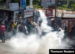 FILE - A man throws a tear gas canister back at the police during a protest against Haiti's President Jovenel Moise, in Port-au-Prince, Feb. 10, 2021.