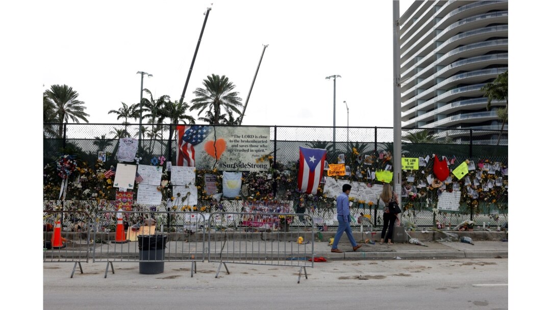 A man walks past a makeshift memorial site as search and rescue efforts resume the day after the managed demolition of the remaining part of Champlain Towers South complex, in Surfside, Florida, July 5, 2021.