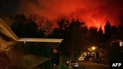 Muškarac ispred kuće dok požari u Pacifik Palisejds gore prema četvrti Ensino u Los Anđelesu, 10. januara 2025. (Foto: AFP/Agustin Paullier)