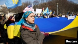 A woman in Washington sings Ukraine's national anthem while holding the national flag during a 2014 protest against Russia's aggression in Ukraine.