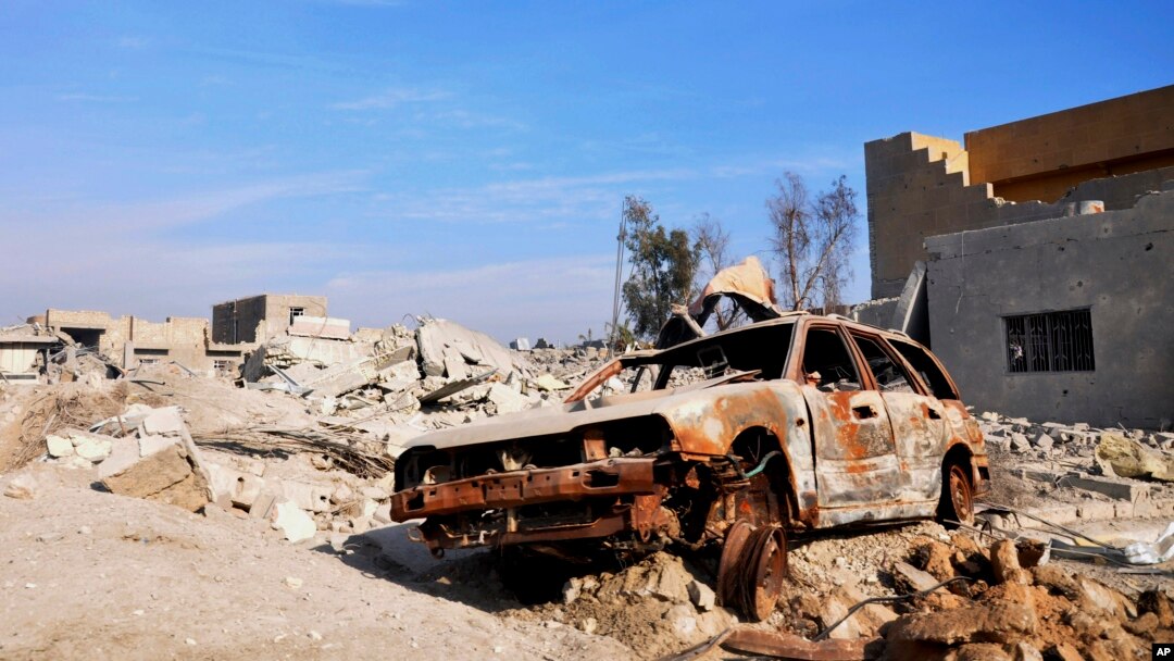 A burned out car lies amid damaged buildings in Ramadi, 70 miles (115 kilometers) west of Baghdad, Iraq, on Jan. 2, 2016. Iraq's military says Islamic State militants launched attacks Friday with seven suicide car bombs.