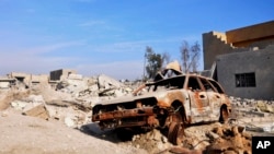 A burned out car lies amid damaged buildings in Ramadi, 70 miles (115 kilometers) west of Baghdad, Iraq, on Jan. 2, 2016. Iraq's military says Islamic State militants launched attacks Friday with seven suicide car bombs.