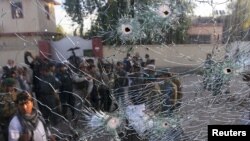 Afghan security forces are seen from a cracked side window of a vehicle, which was damaged in a suicide attack on a police headquarters in Jalalabad, Afghanistan, June 1, 2015.