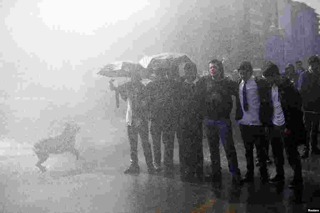 Students gather as a jet of water is released from a riot police vehicle during a demonstration to demand changes in the education system, in Santiago, Chile.