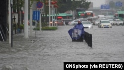 中國河南省鄭州市一名市民站在洪水氾濫的街道上。（2021年7月20日）
