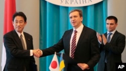 FILE - Japanese Foreign Minister Fumio Kishida, left, and Minister of Economical Development and Trade of Ukraine Pavlo Sheremeta, center, exchange signed documents while meeting in Kyiv,Ukraine, July 17, 2014. 