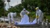 Volunteers wearing personal protective equipment (PPE) suits bury the body of a person suspected of dying from the Covid-19 coronavirus at a cemetery, in Yangon on October 26, 2020. (Photo by Ye Aung THU / AFP)