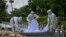 Volunteers wearing personal protective equipment (PPE) suits bury the body of a person suspected of dying from the Covid-19 coronavirus at a cemetery, in Yangon on October 26, 2020. (Photo by Ye Aung THU / AFP)