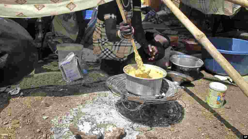 Uma mulher deslocada de guerra cozinha a farinha de milho no campo de refugiados em Juba. Dez. 23, 2013.