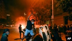 Demonstrators vandalize a car as they protest the death of George Floyd, May 31, 2020, near the White House in Washington.