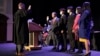 In this photo provided by Peg Shanahan, Lowell District Court Judge Stephen Geary, left, swears in new Cambodian-American Mayor Sokhary Chau, Monday, Jan. 3, 2022, in Lowell, Massachusetts, as Chau's family stands with him. 