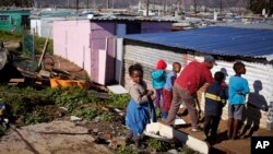 Children paint a shack with white fire retardant paint as part of their contribution to International Nelson Mandela day celebrating former South African president Mandela birth day in the township of Nomzamo, South Africa, July 18, 2015. 