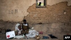 Displaced pygmies sit with their belongings outside a classroom, which serves as their shelter by night, Dec. 16, 2017 in Oicha. Attacks allegedly carried out by the Ugandan Muslim Group, ADF in Eastern Democratic Republic of the Congo (DRC), have displaced thousands of Pygmies.