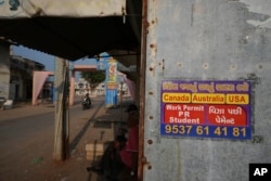 An advertizing  poster pasted connected  a store  astatine  Dingucha colony   successful  Gandhinagar, India, Nov. 12, 2024. The poster reads successful  Gujarati "Make your imagination  of going overseas  travel  true," connected  apical  and "Payment aft  visa."