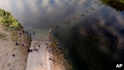 Migrantes, entre ellos haitianos, vadean de un lado a otro entre Texas y México el Río Grande, el 22 de septiembre de 2021, en Del Río, Texas. 