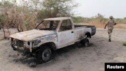 A Nigerian soldier walks past a burnt vehicle during a military patrol in Hausari village, near Maiduguri, June 5, 2013. 