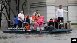 Sekelompok warga sedang dievakuasi dari rumah-rumah mereka yang dikepung banjir akibat Badai Tropis Harvey, Minggu 27 Agustus 2017, di Houston, Texas. 