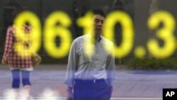 A man is reflected on an electric board showing the Nikkei 225 index in Tokyo, Japan, August 3, 2011