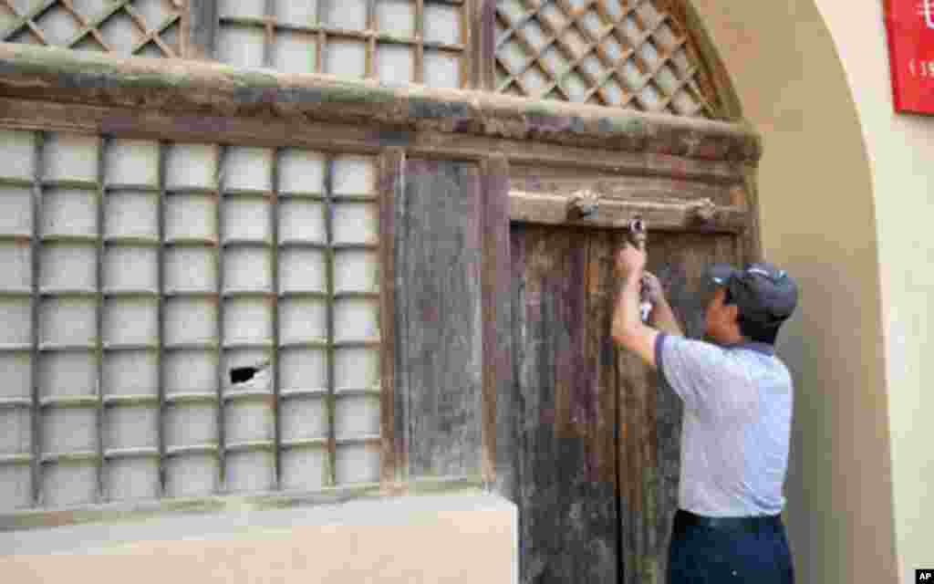 管理员给毛泽东旧居开门，左侧窗户上可以看到一个窟窿