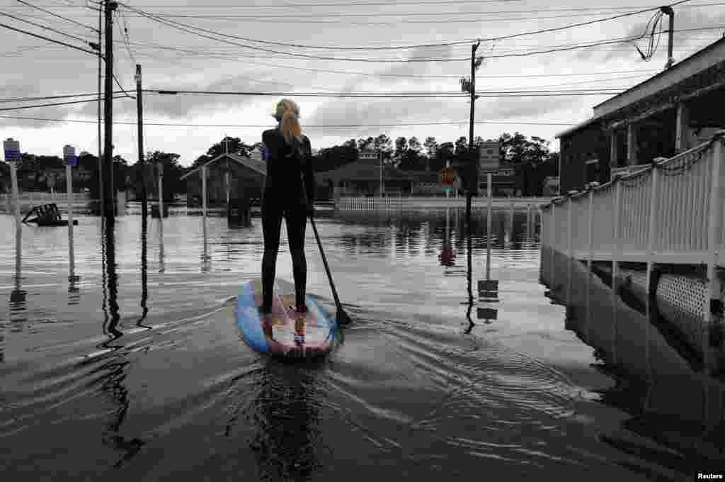 Zoe Jurusik mengarungi jalan yang banjir di atas papan setelah Badai Sandy di Pantai Bethany, Delaware, 30 Oktober 2012.