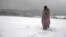 A migrant walks through the snow wrapped in a blanket at the Lipa camp northwestern Bosnia, near the border with Croatia, Saturday, Dec. 26, 2020.