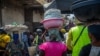 FILE - Women carry goods on their head as they walk in the Dantokpa market, one of the largest open-air market in West Africa, in Cotonou, Benin, on Feb. 29, 2024. 