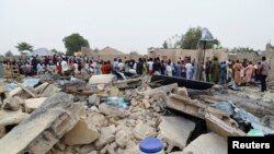 Mutane sunyi dafifi kewaye da inda daya daga cikin boma-boman ya tashi domin ganewa idanusu a Ajilari-Gomari kusa da filin jirgin sama na Maiduguri a ranar 2 ga watan Maris 2014.