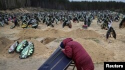 Seorang perempuan tampak meratapi peti jenazah yang berisi saudaranya yang tewas di tempat pemakaman di Irpin, Kyiv, pada 17 April 2022. Saudaranya tewas dalam serangan yang dilakukan oleh pasukan Rusia. (Foto: Reuters/Gleb Garanich)