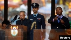 India's President Pranab Mukherjee speaks at the podium as the fake sign language interpreter (R) punches the air beside him during a memorial service for Nelson Mandela, in Johannesburg, Dec. 10, 2013.