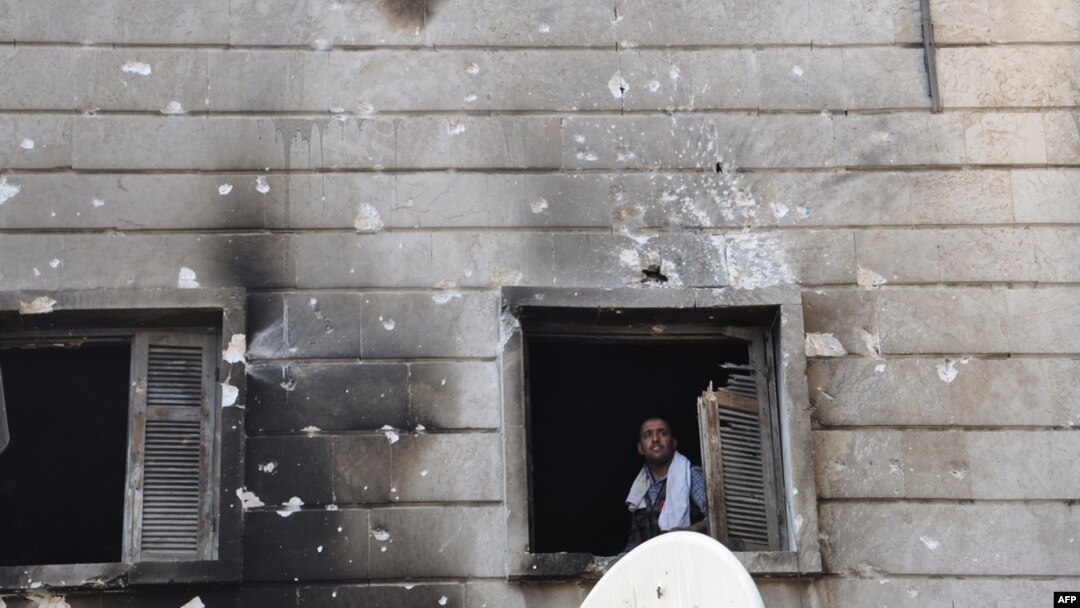 Free Syrian Army fighter looks out from the window of the burnt Shaar district police station in the northern Syrian city of Aleppo after it was overrun by rebel fighters on July 25, 2012. 