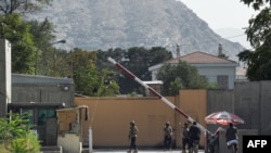 Afghan security personnel stand guard in front of a gate in the Green Zone in Kabul, Aug. 15, 2021.