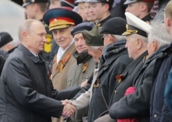 FILE - Russian President Vladimir Putin shakes hands with veterans after the the Victory Day military parade marking the World War II anniversary at Red Square in Moscow, May 9, 2017.