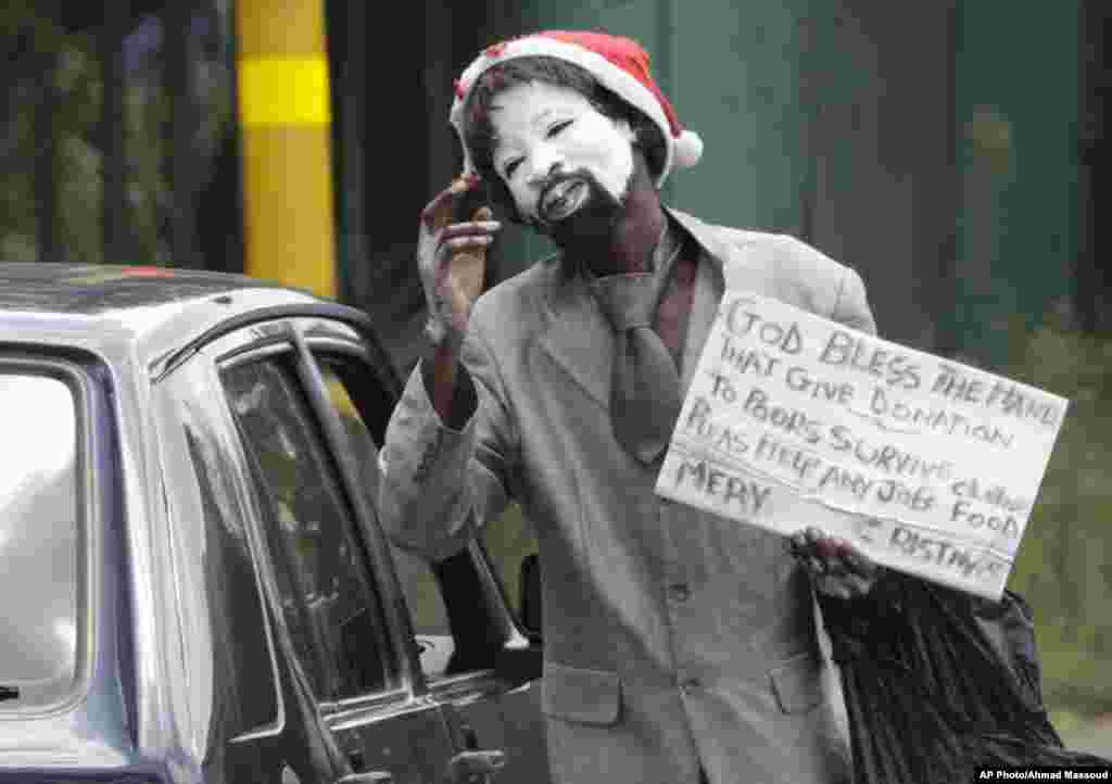 A mime artist wearing a Christmas hat begs on a street corner in a Johannesburg suburb, .