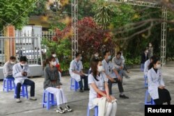 FILE - Health workers wait to be vaccinated against COVID-19 at Hai Duong Hospital for Tropical Diseases, Hai Duong province, Vietnam, March 8, 2021.