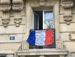 A French flag outside a Paris apartment urges people to stay at home and thanks health care workers. (Lisa Bryant/VOA)